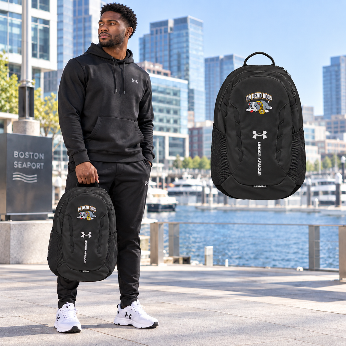 Black adult model holding the On Dead Dogs Under Armour Backpack at Boston Seaport with matching floating backpack.