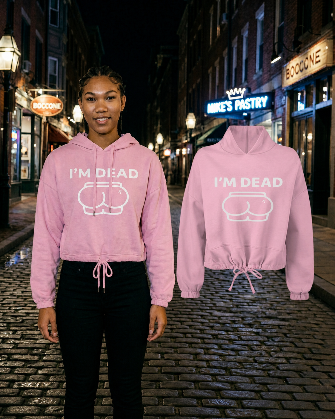 Female model wearing the Light Pink Im Dead cropped hoodie beside the matching floating garment on a Boston cobblestone street