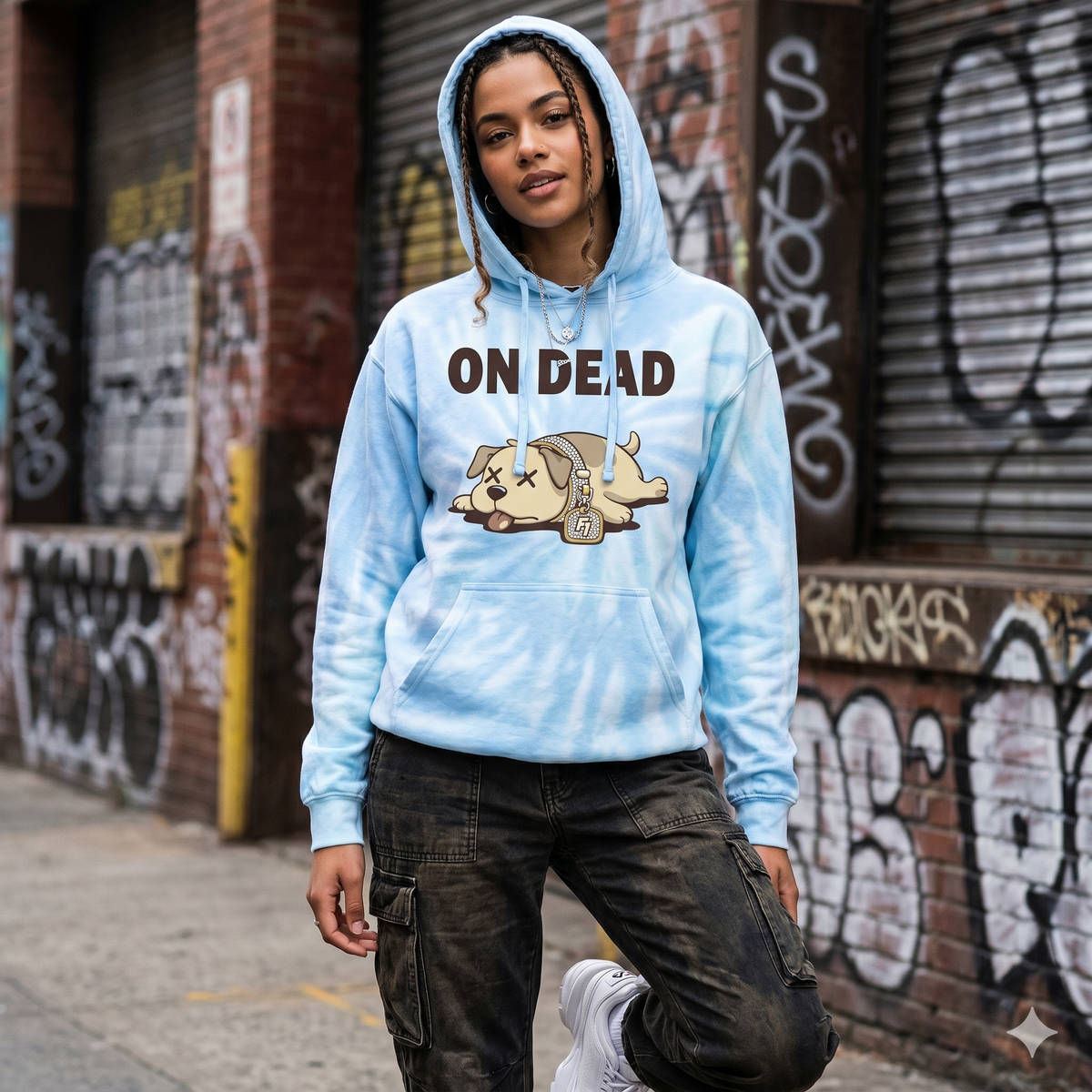 Person wearing a blue tie-dye hoodie with 'ON DEAD' and a graphic design, standing in front of a graffiti-covered wall.