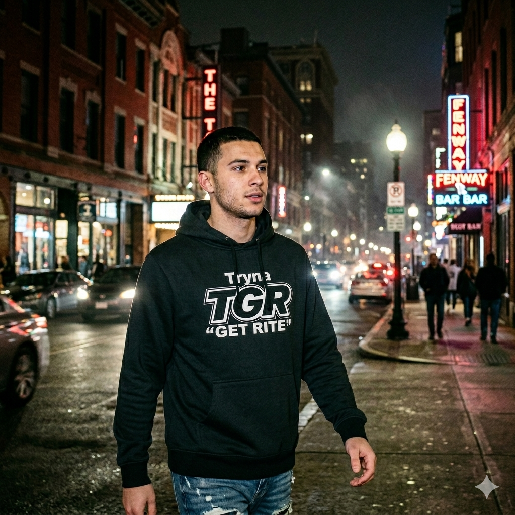 Man wearing a black hoodie with 'TGR' logo on a city street at night.