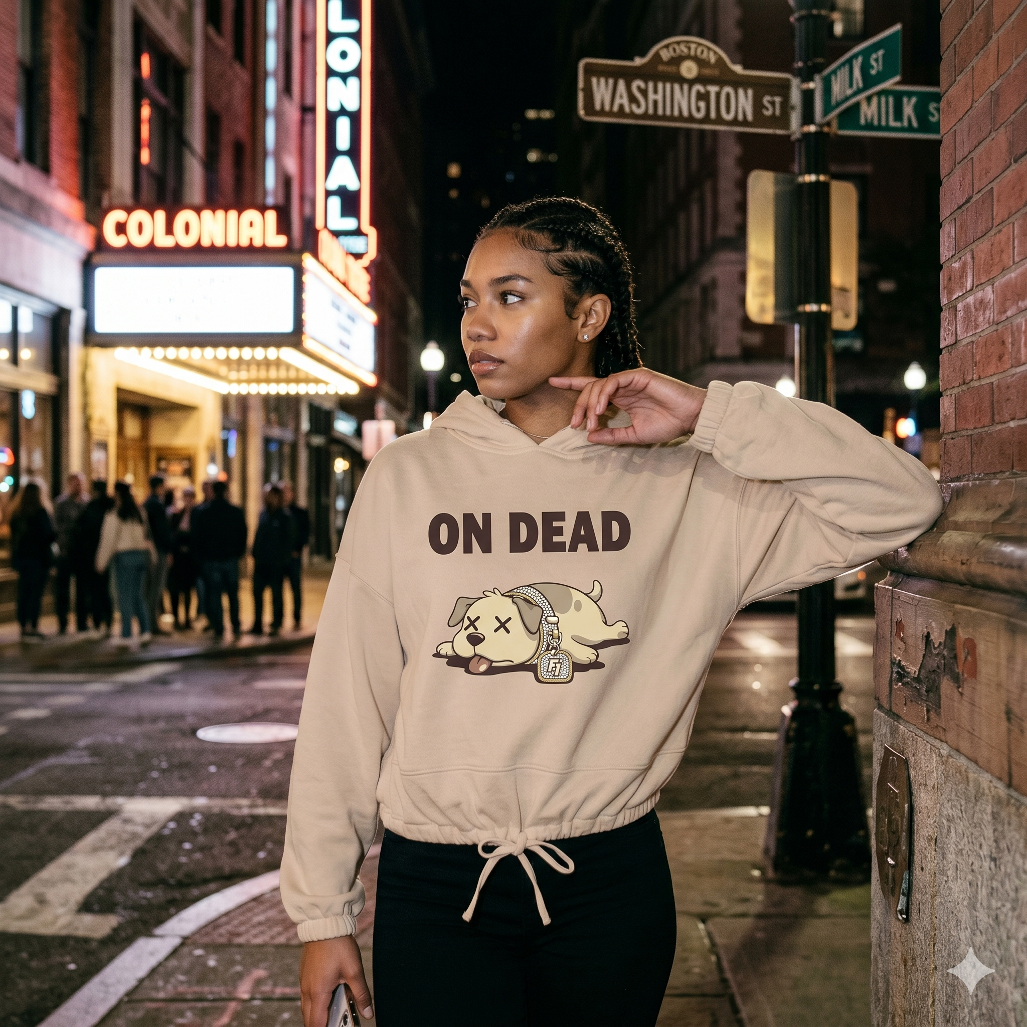 Person wearing a beige hoodie with 'ON DEAD' text and graphic on a city street at night.