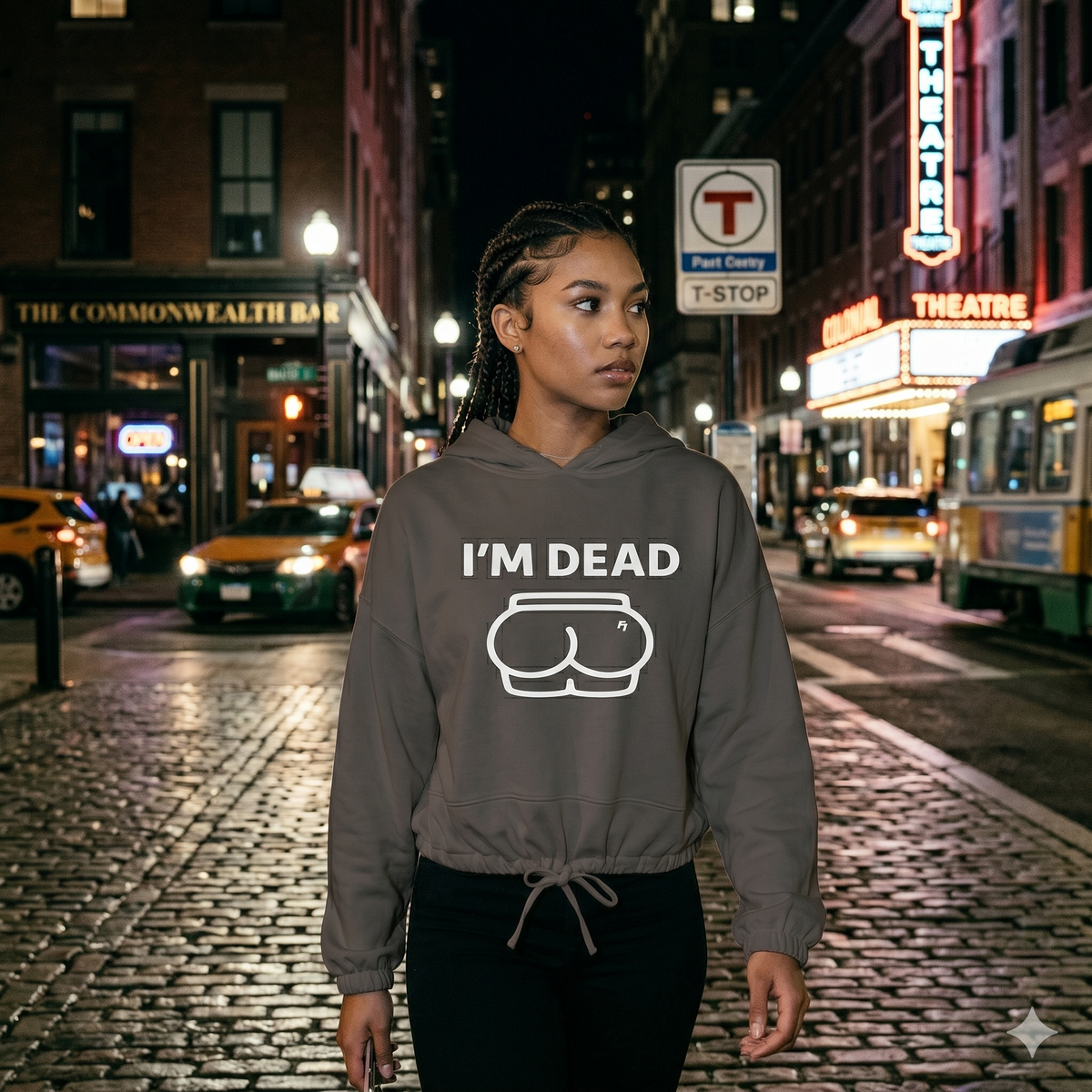 Person wearing a hoodie with 'I'm Dead' text on a city street at night.