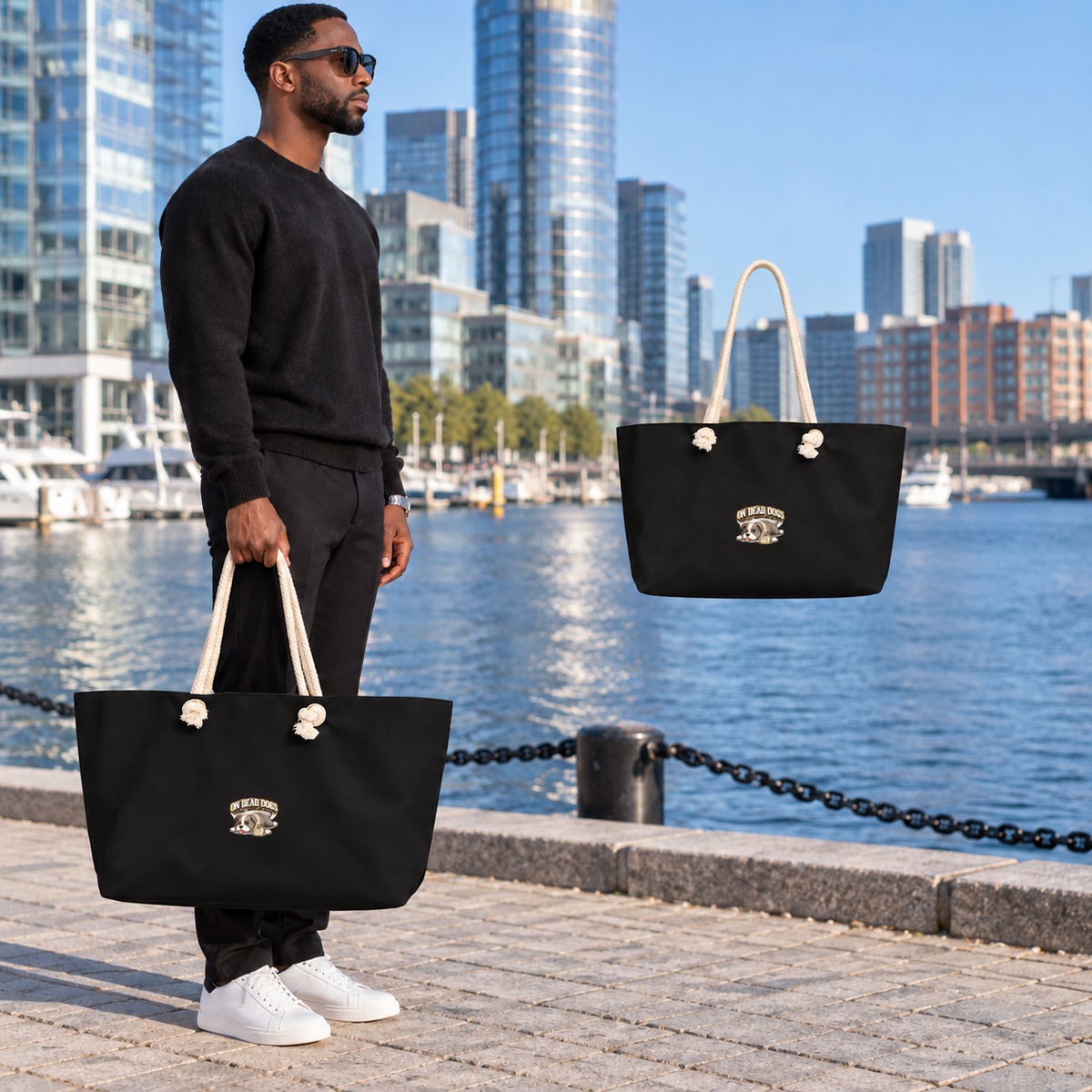 Black adult model carrying the On Dead Dogs Weekender Bag in Boston, with matching floating rope-handle bag.